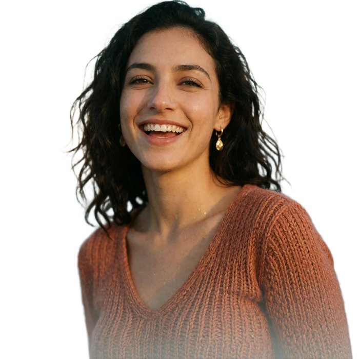 Jordanian woman in a terracotta knit top laughing softly while glancing off-camera