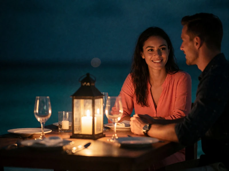 Maldivian woman and Western man talking closely over a candlelit seaside dinner table